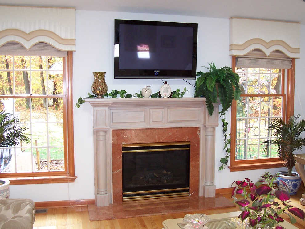 Klassisk inredning av ett mellanstort allrum med öppen planlösning, med ett finrum, vita väggar, ljust trägolv, en standard öppen spis, en spiselkrans i trä och en väggmonterad TV