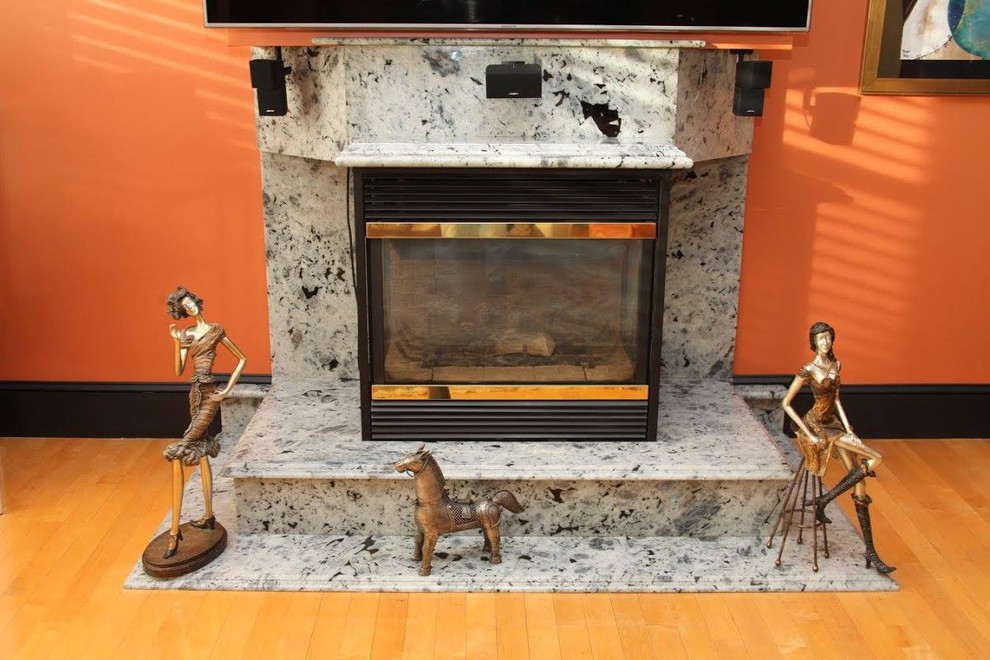 ボストンにあるお手頃価格の中くらいなエクレクティックスタイルのおしゃれなリビング (オレンジの壁、淡色無垢フローリング、標準型暖炉、石材の暖炉まわり、壁掛け型テレビ、ベージュの床) の写真