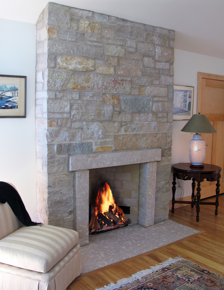 Example of a classic enclosed medium tone wood floor living room design in Other with white walls, a standard fireplace and a stone fireplace
