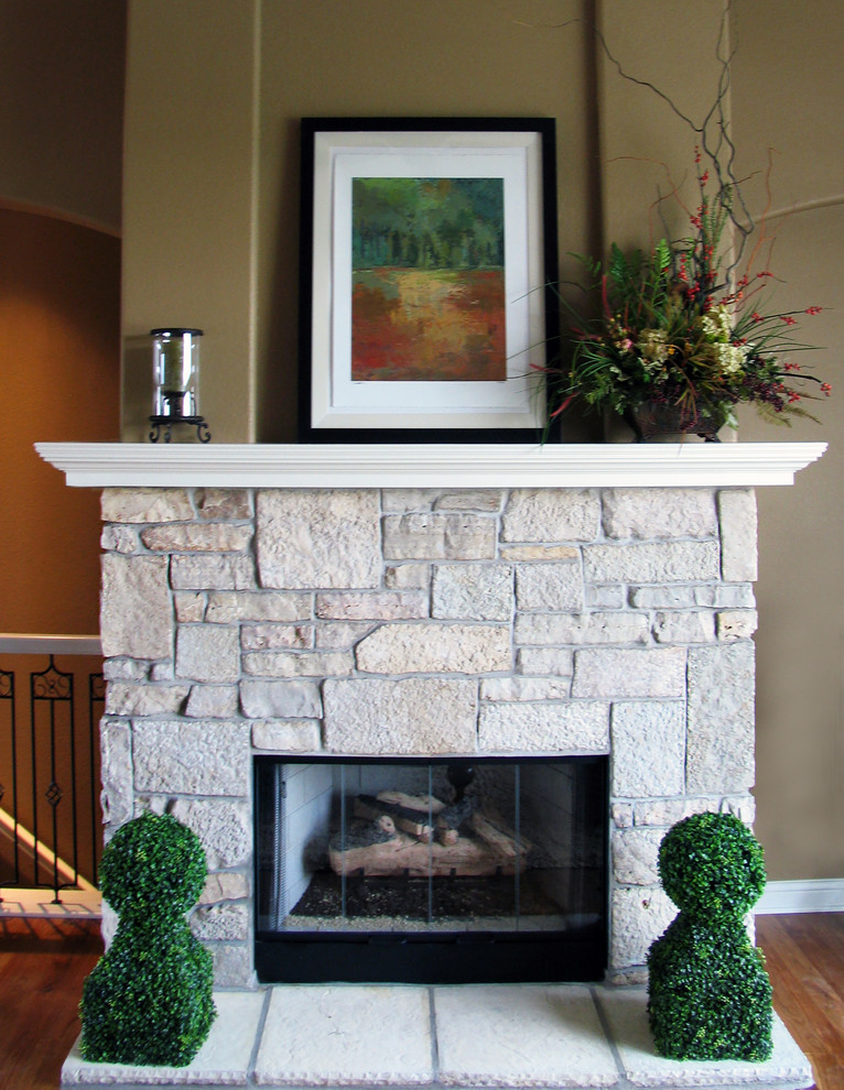 他の地域にあるお手頃価格の中くらいなトラディショナルスタイルのおしゃれなLDK (ベージュの壁、無垢フローリング、標準型暖炉、石材の暖炉まわり) の写真