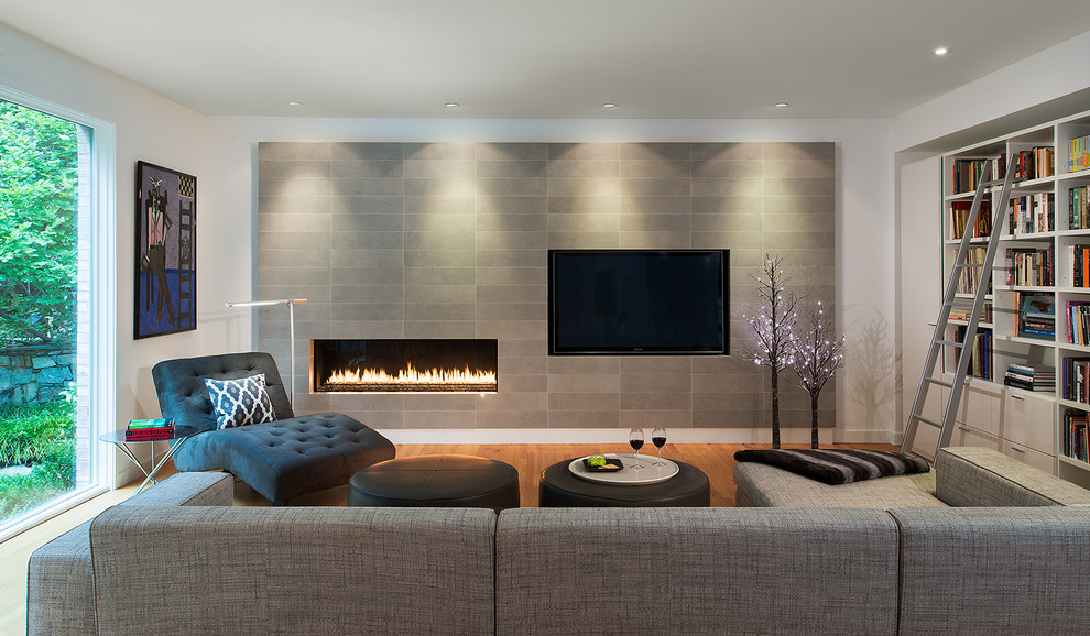 Inspiration for a contemporary living room in DC Metro with a reading nook, white walls, medium hardwood flooring, a ribbon fireplace, a tiled fireplace surround, a wall mounted tv and feature lighting.