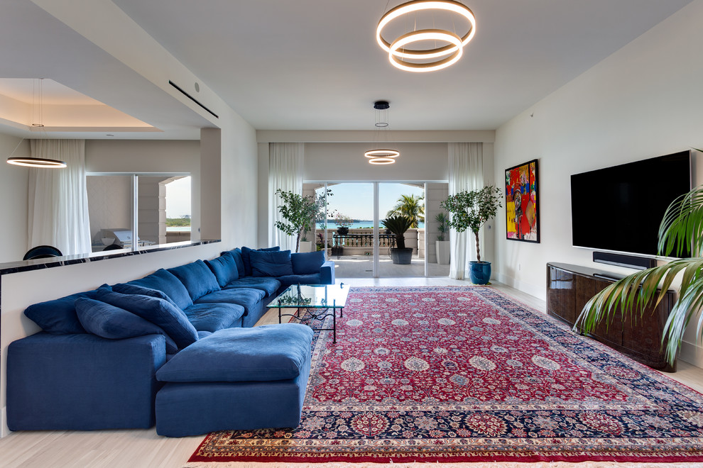 На фото: большая открытая гостиная комната в современном стиле с белыми стенами, полом из керамической плитки, телевизором на стене и бежевым полом без камина с
