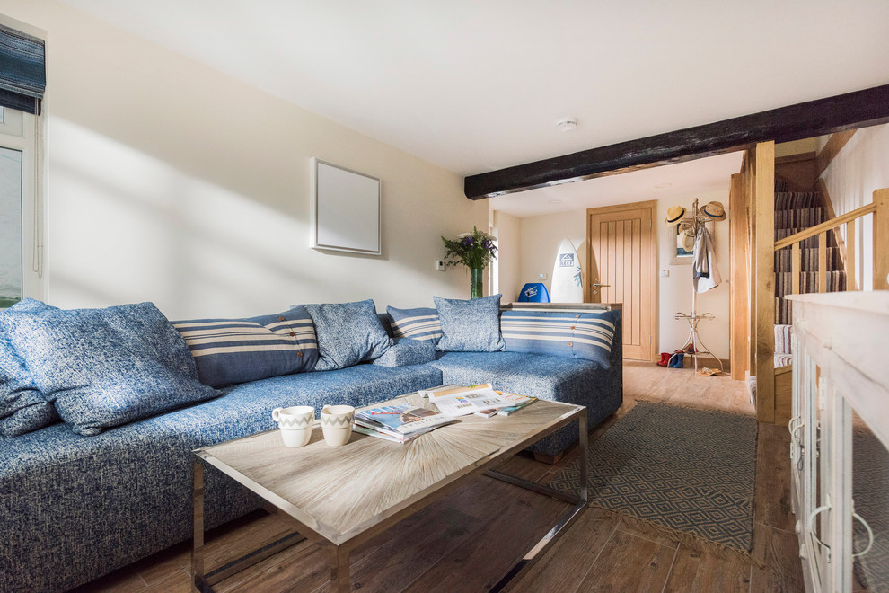 Стильный дизайн: гостиная комната в морском стиле с синим диваном - последний тренд