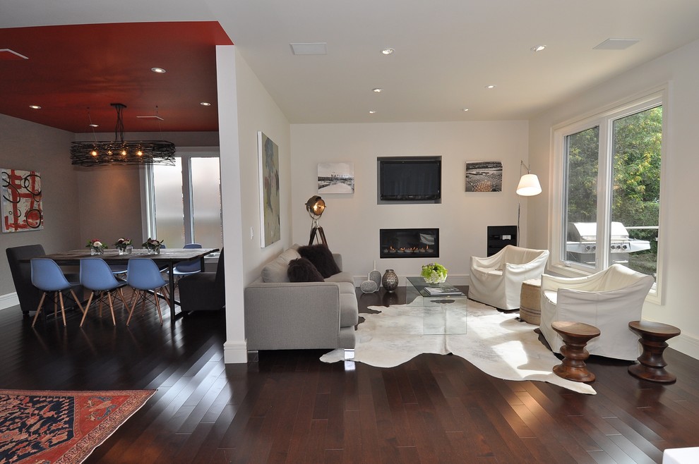 На фото: гостиная комната в стиле модернизм с белыми стенами, стандартным камином и телевизором на стене с