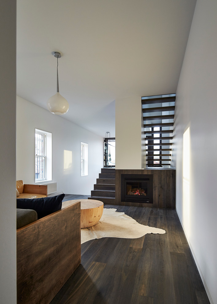 Idee per un soggiorno minimal aperto con pareti bianche, parquet scuro, camino classico e cornice del camino in legno