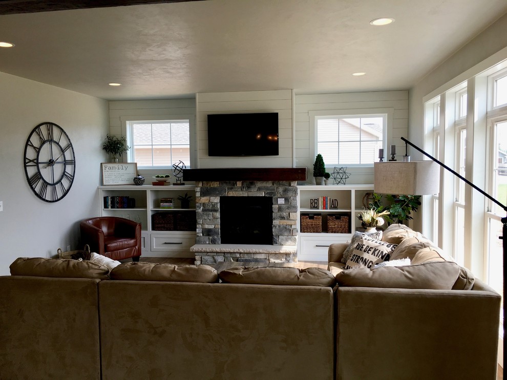 Bild på ett mellanstort lantligt allrum med öppen planlösning, med en hemmabar, grå väggar, vinylgolv, en standard öppen spis, en spiselkrans i sten, en inbyggd mediavägg och brunt golv