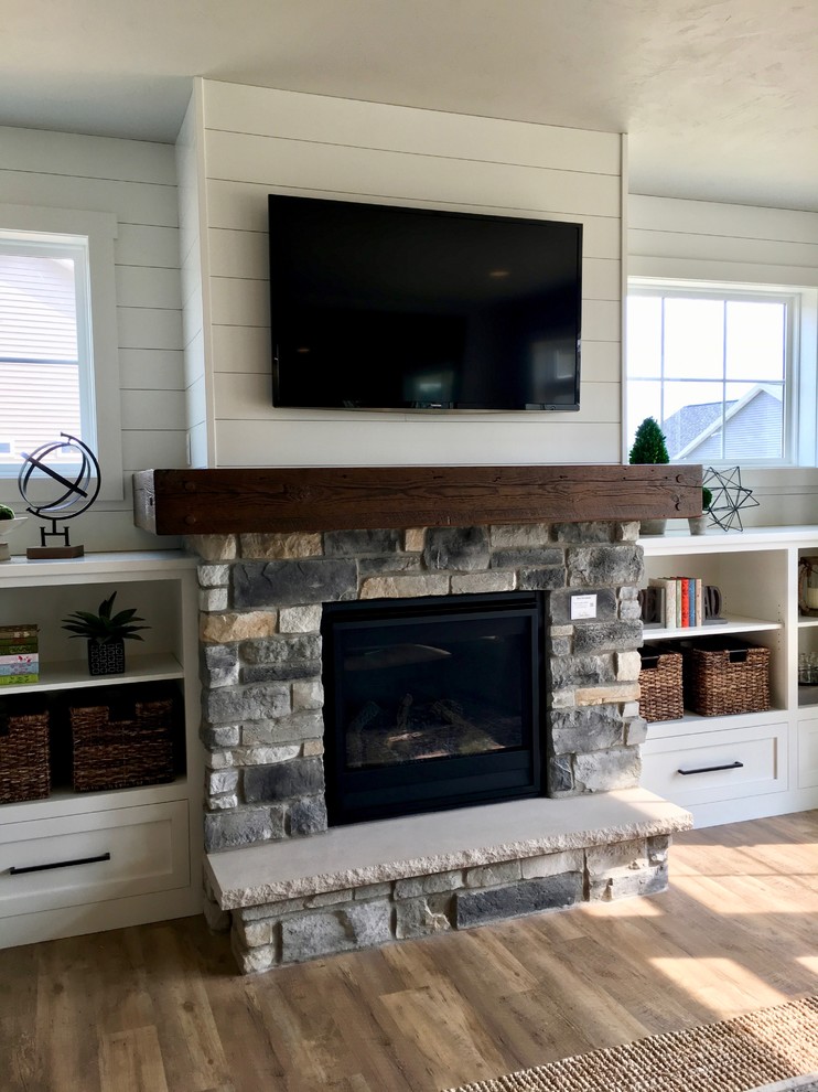 Large country open plan living room in Other with a home bar, grey walls, vinyl flooring, a standard fireplace, a stone fireplace surround, a built-in media unit and brown floors.