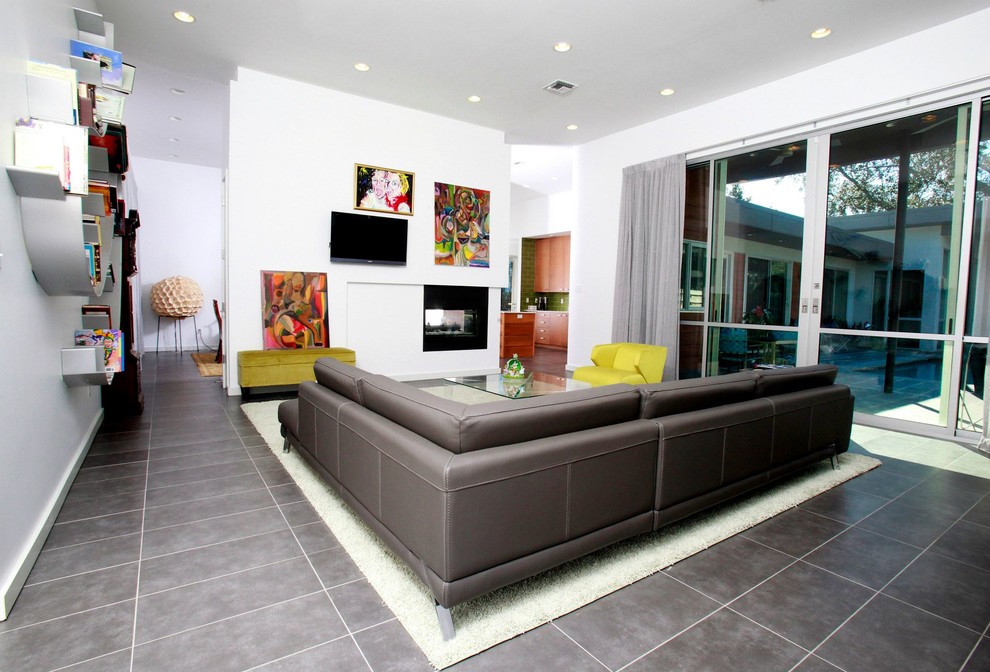 Стильный дизайн: гостиная комната в стиле модернизм с двусторонним камином и белыми стенами - последний тренд