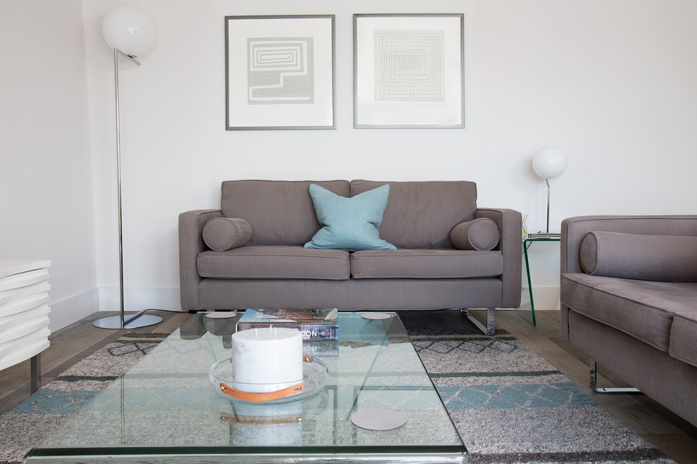 This is an example of a medium sized scandinavian enclosed living room in London with white walls, medium hardwood flooring, a freestanding tv and grey floors.