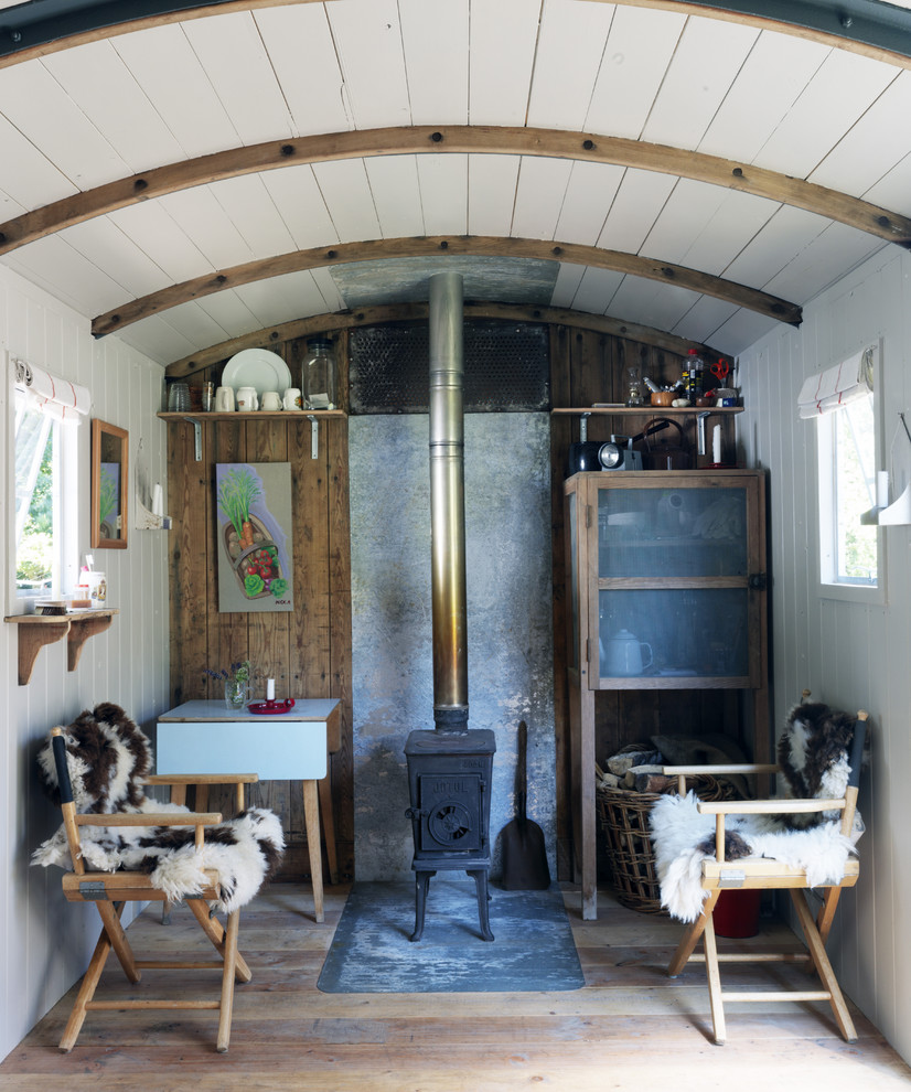 Cette photo montre un petit salon romantique avec un mur blanc et un poêle à bois.