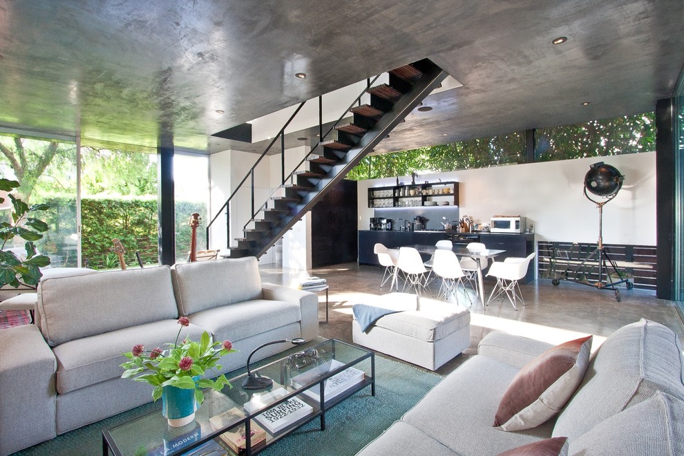 Immagine di un soggiorno design aperto e di medie dimensioni con pavimento in cemento, pareti bianche, pavimento grigio e TV a parete