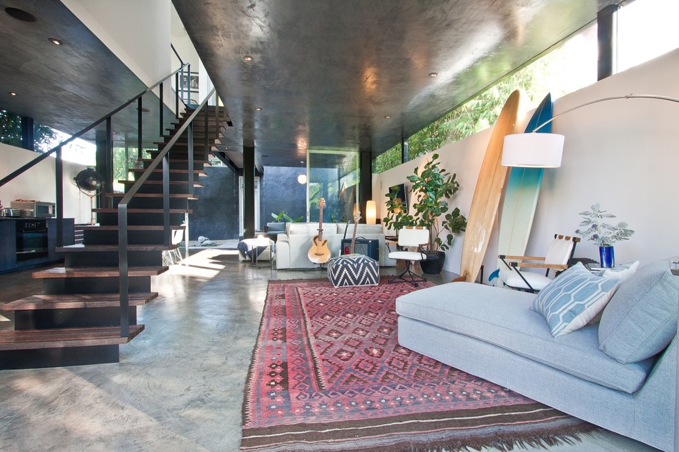 Esempio di un soggiorno design di medie dimensioni e aperto con pareti bianche, pavimento in cemento, TV a parete e pavimento grigio