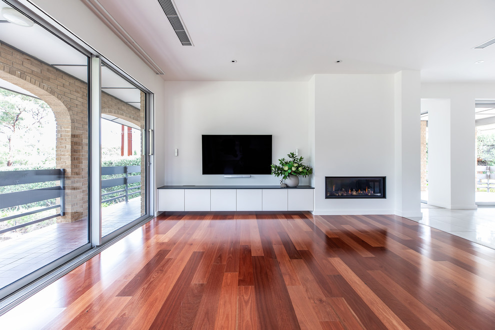 Mittelgroßes, Offenes Modernes Wohnzimmer mit weißer Wandfarbe, braunem Holzboden, Hängekamin, verputzter Kaminumrandung, TV-Wand und rotem Boden in Adelaide