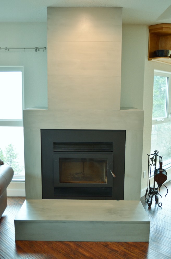 Offenes Modernes Wohnzimmer mit weißer Wandfarbe, braunem Holzboden, Kaminofen und Kaminumrandung aus Beton in Vancouver