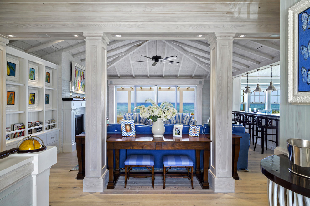 На фото: открытая гостиная комната среднего размера в морском стиле с белыми стенами, паркетным полом среднего тона, стандартным камином и синим диваном без телевизора
