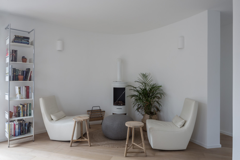 Esempio di un soggiorno moderno di medie dimensioni e aperto con libreria, pareti bianche, pavimento in legno massello medio, stufa a legna, TV a parete e pavimento marrone