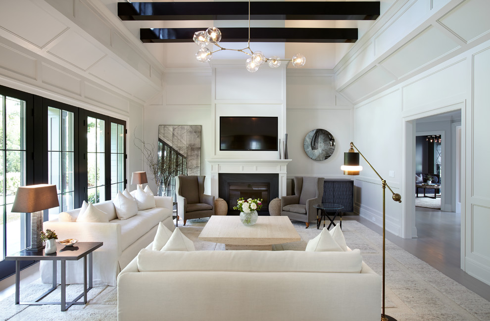 Esempio di un soggiorno classico chiuso con pareti bianche, pavimento in legno massello medio, camino classico, TV a parete e pavimento grigio