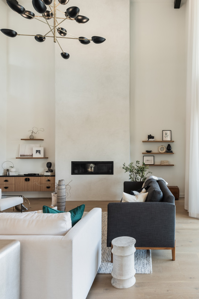 Diseño de salón abierto moderno grande con paredes blancas, suelo de madera clara, todas las chimeneas, marco de chimenea de yeso, televisor colgado en la pared y suelo beige