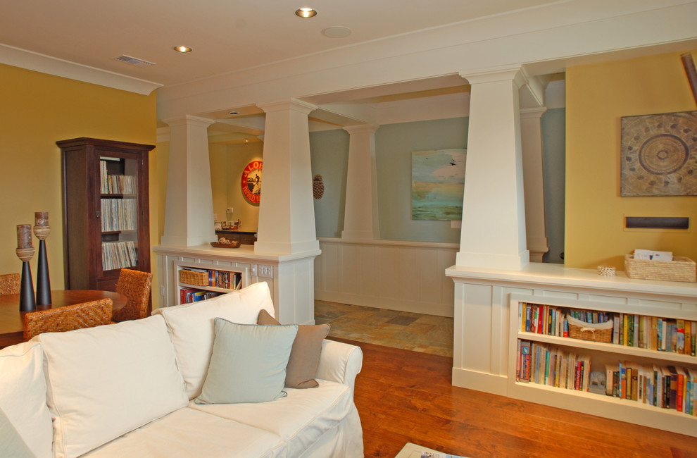 На фото: открытая гостиная комната среднего размера в стиле кантри с с книжными шкафами и полками, желтыми стенами, паркетным полом среднего тона и оранжевым полом без камина, телевизора