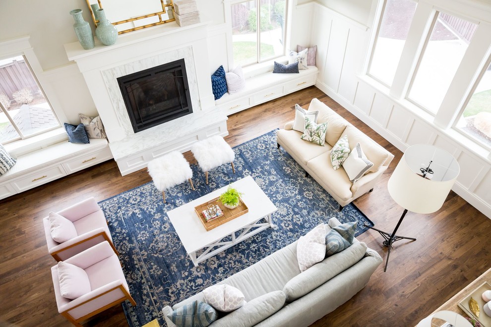 Cette image montre un grand salon design avec un mur blanc, un sol en bois brun et un manteau de cheminée en pierre.