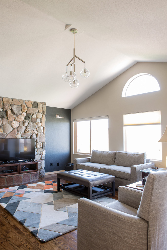 Medium sized traditional open plan living room in Denver with black walls, medium hardwood flooring, no fireplace, a stone fireplace surround, a freestanding tv and brown floors.
