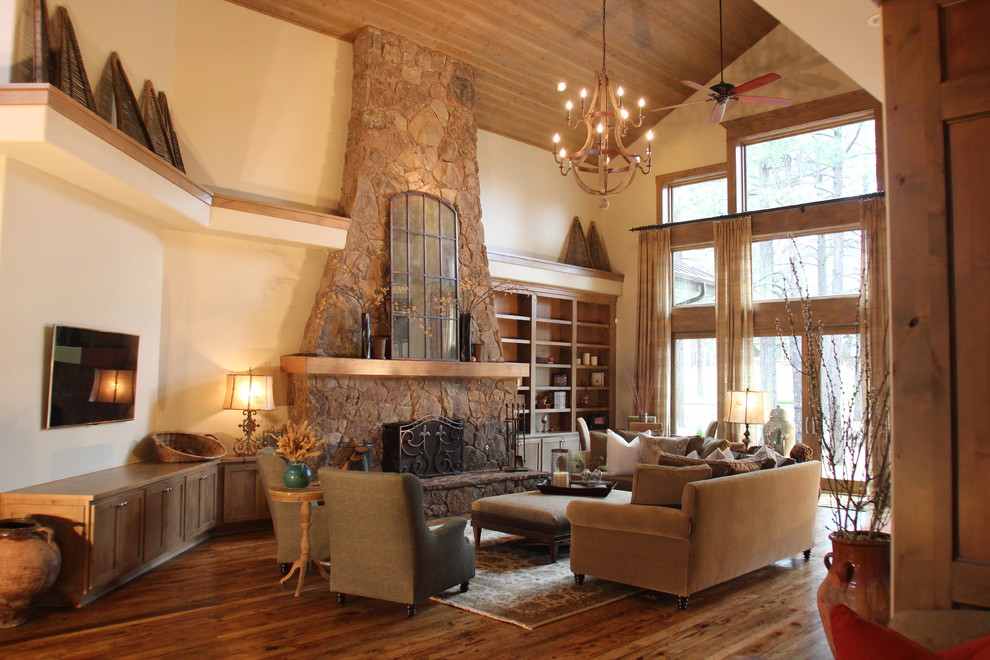 Cette image montre un grand salon craftsman ouvert avec une salle de réception, un mur blanc, un sol en bois brun, une cheminée standard et un manteau de cheminée en pierre.