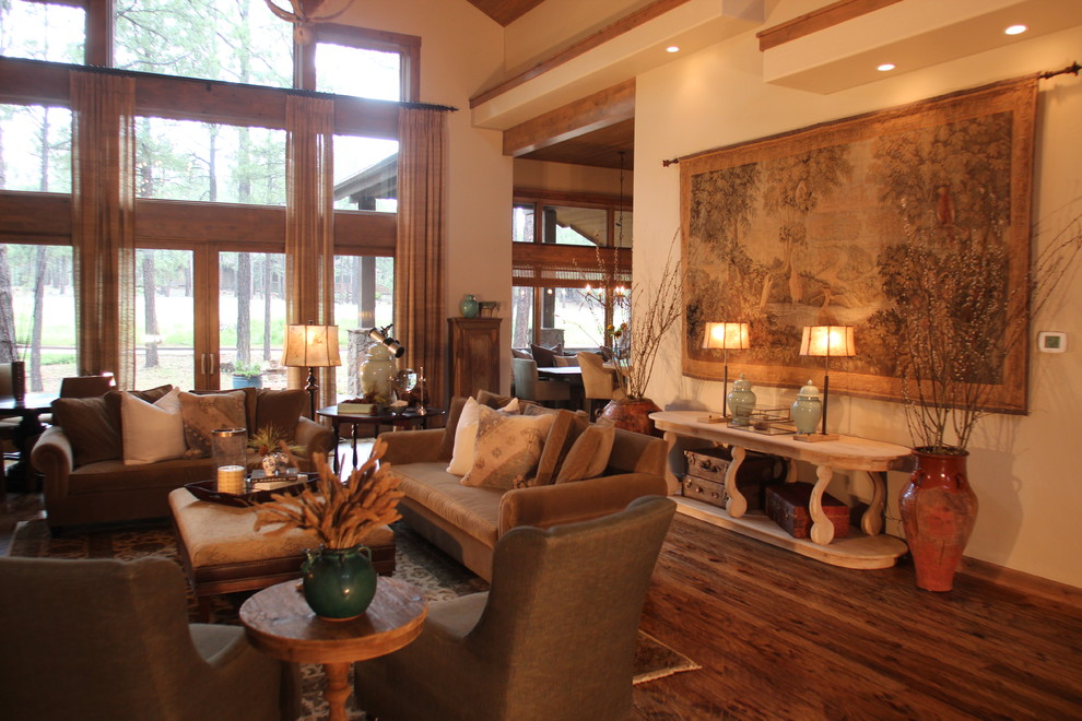 Cette photo montre un grand salon craftsman ouvert avec une salle de réception, un mur blanc, un sol en bois brun, une cheminée standard et un manteau de cheminée en pierre.