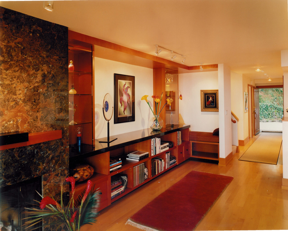 Imagen de biblioteca en casa abierta contemporánea de tamaño medio sin televisor con paredes blancas, suelo de madera clara, todas las chimeneas, marco de chimenea de piedra y suelo amarillo