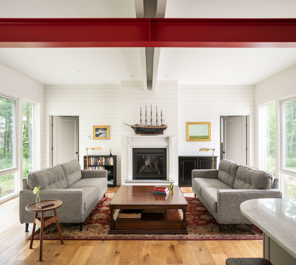 Offenes Landhaus Wohnzimmer mit weißer Wandfarbe, braunem Holzboden, Kamin und braunem Boden in Portland Maine