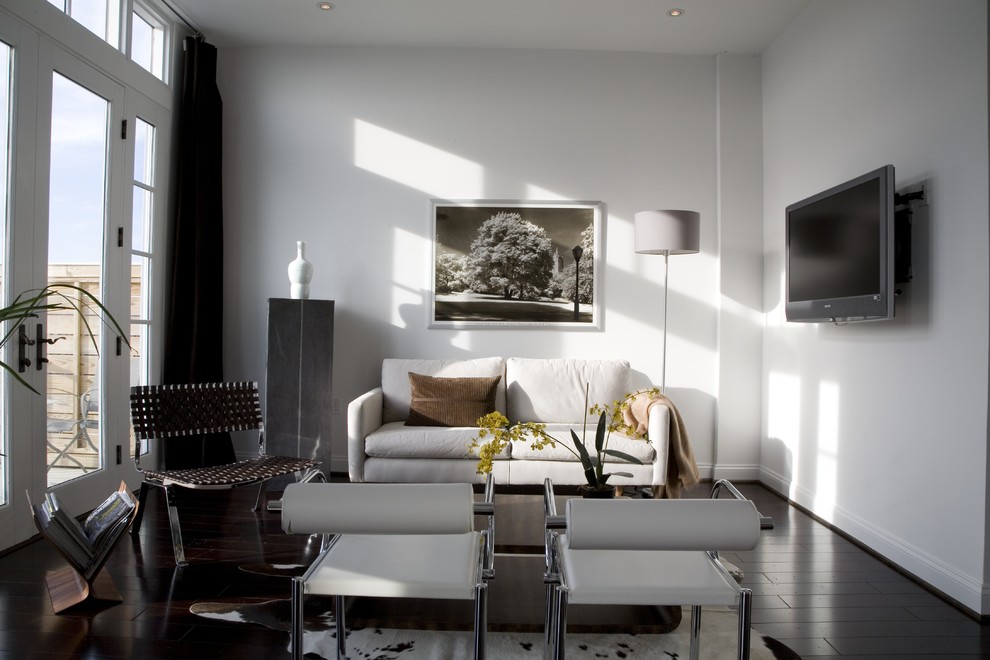 Источник вдохновения для домашнего уюта: гостиная комната в современном стиле с белыми стенами, темным паркетным полом, телевизором на стене и черным полом