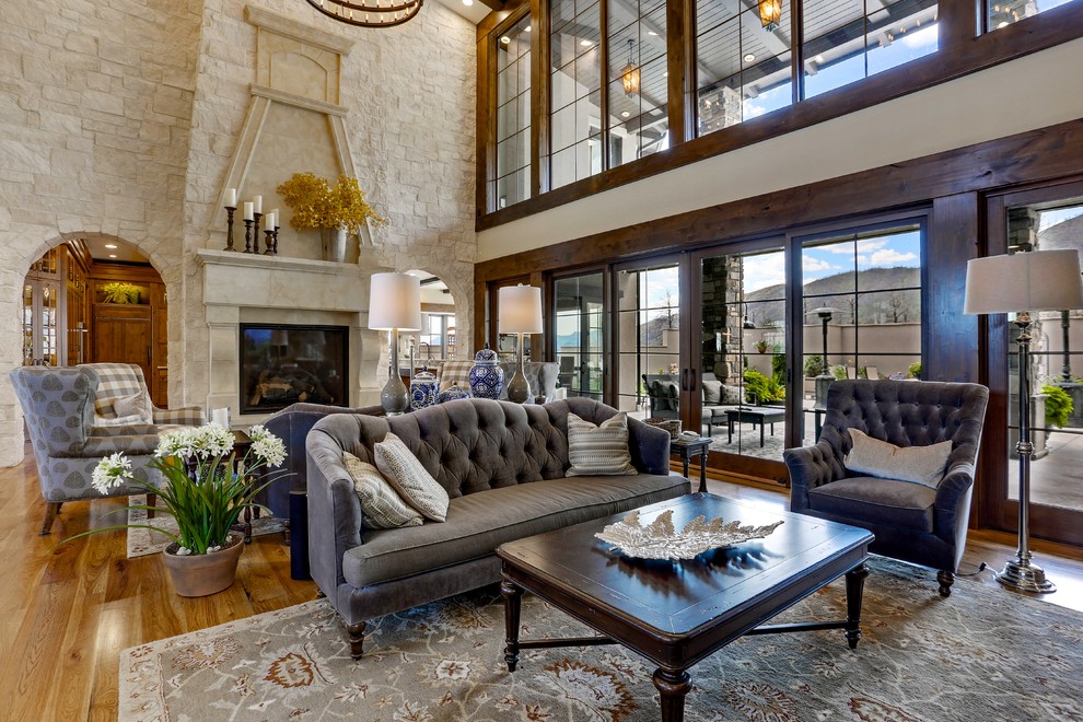 Example of a huge tuscan enclosed and formal light wood floor and brown floor living room design in Denver with yellow walls, a standard fireplace, a stone fireplace and a concealed tv