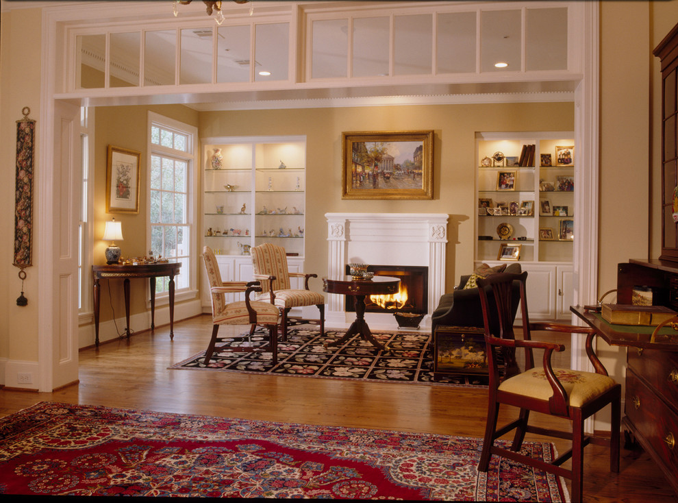 Imagen de salón para visitas cerrado de estilo americano de tamaño medio con paredes amarillas, suelo de madera clara, todas las chimeneas y marco de chimenea de madera