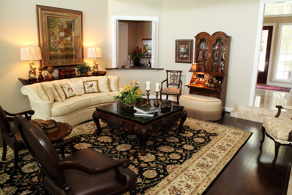 Modelo de salón para visitas tradicional con paredes beige, suelo de madera oscura, chimenea de esquina, marco de chimenea de yeso y suelo marrón