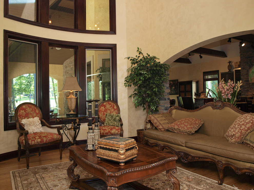 Foto di un grande soggiorno chic aperto con sala formale, pareti beige, pavimento in legno massello medio, camino classico e cornice del camino piastrellata