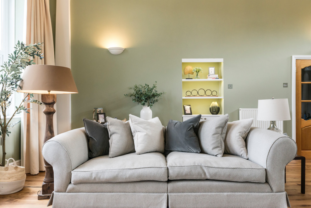 Klassisk inredning av ett stort separat vardagsrum, med ett finrum, gröna väggar, mellanmörkt trägolv, en standard öppen spis, en spiselkrans i trä, en fristående TV och brunt golv