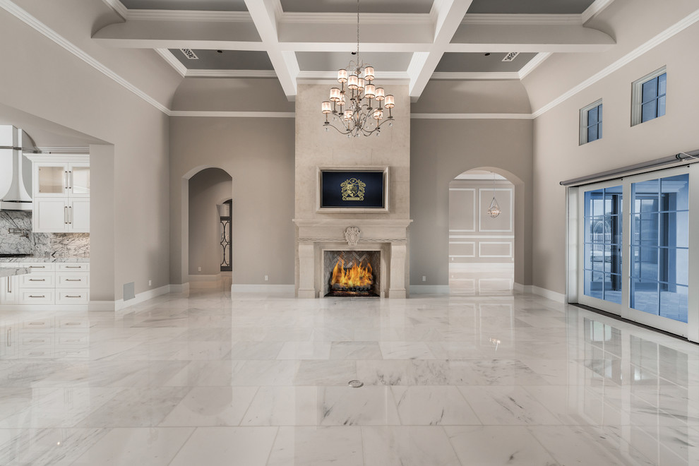 フェニックスにあるラグジュアリーな巨大なトランジショナルスタイルのおしゃれなリビング (大理石の床、石材の暖炉まわり、壁掛け型テレビ、標準型暖炉、ベージュの壁、グレーの床) の写真