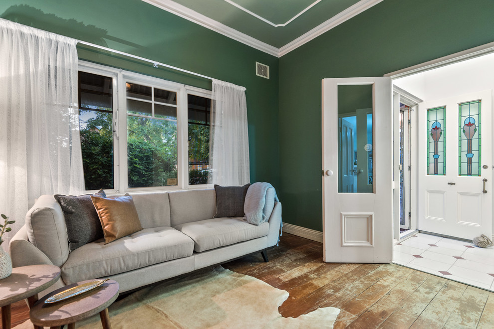 На фото: парадная, изолированная гостиная комната в стиле фьюжн с зелеными стенами и темным паркетным полом с
