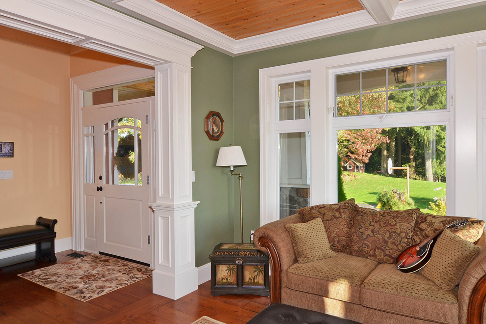 Immagine di un soggiorno american style di medie dimensioni e chiuso con pareti verdi, parquet scuro, camino classico e cornice del camino in pietra