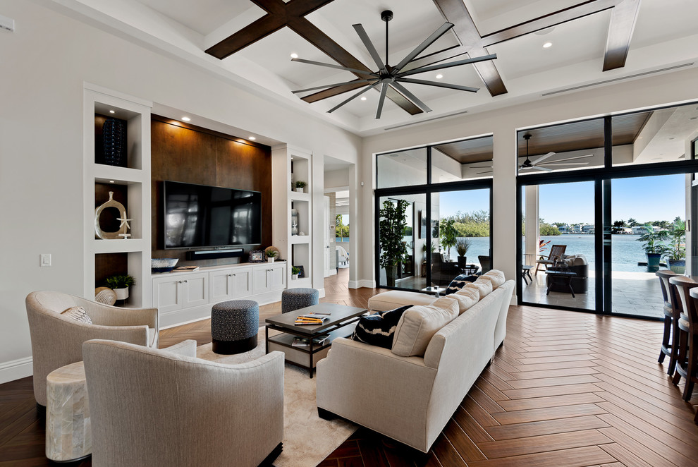 Example of a transitional open concept medium tone wood floor and brown floor living room design in Other with gray walls and a media wall