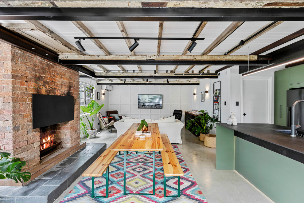 Идея дизайна: открытая гостиная комната в стиле модернизм с белыми стенами, бетонным полом, стандартным камином и фасадом камина из кирпича