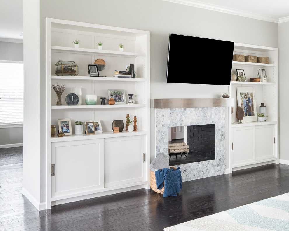 На фото: большая открытая гостиная комната в стиле неоклассика (современная классика) с серыми стенами, темным паркетным полом, двусторонним камином, фасадом камина из плитки, телевизором на стене и коричневым полом
