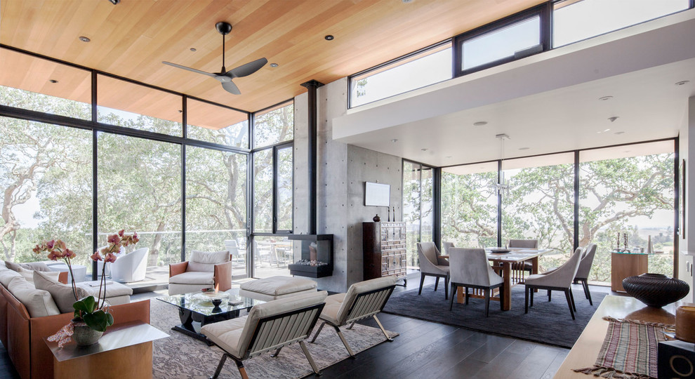 Diseño de salón abierto actual con paredes grises, suelo de madera oscura y todas las chimeneas