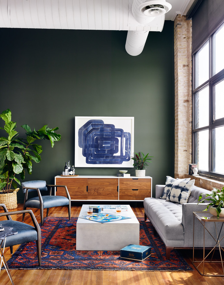 Inspiration for an industrial open concept medium tone wood floor living room remodel in Other with green walls, no fireplace and no tv
