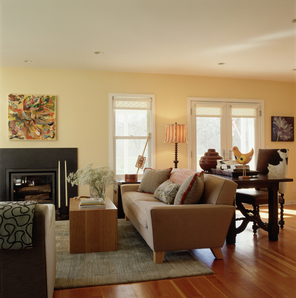 Стильный дизайн: открытая гостиная комната в стиле фьюжн с стандартным камином и желтыми стенами - последний тренд