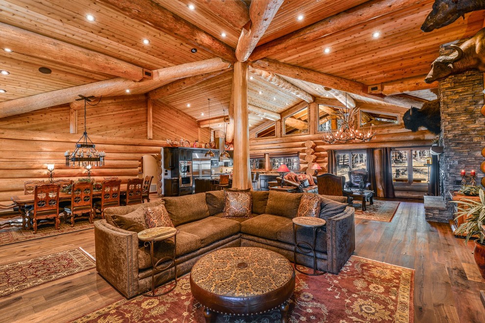Inspiration for a large rustic open plan living room in Phoenix with brown walls, medium hardwood flooring, a standard fireplace, a stone fireplace surround, a built-in media unit and brown floors.