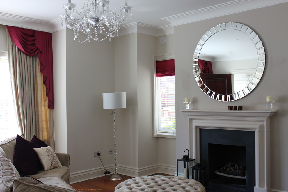 Retro living room in Dublin with medium hardwood flooring, a standard fireplace and a plastered fireplace surround.