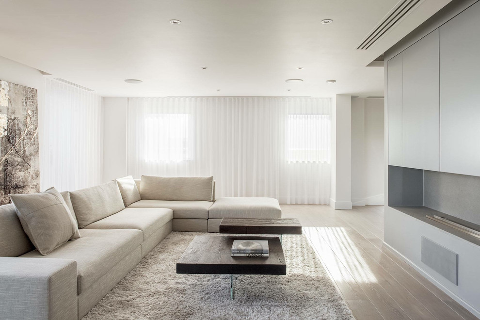 Идея дизайна: гостиная комната в современном стиле с белыми стенами, светлым паркетным полом и скрытым телевизором