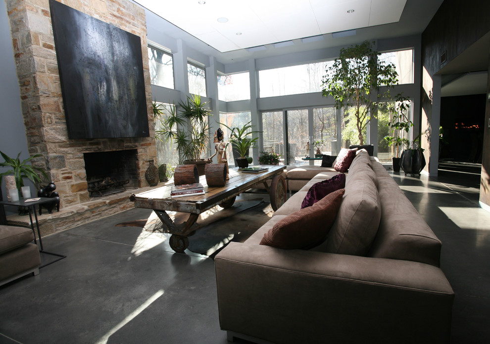 Стильный дизайн: огромная открытая гостиная комната в современном стиле с серыми стенами, бетонным полом, стандартным камином, фасадом камина из камня и серым полом без телевизора - последний тренд