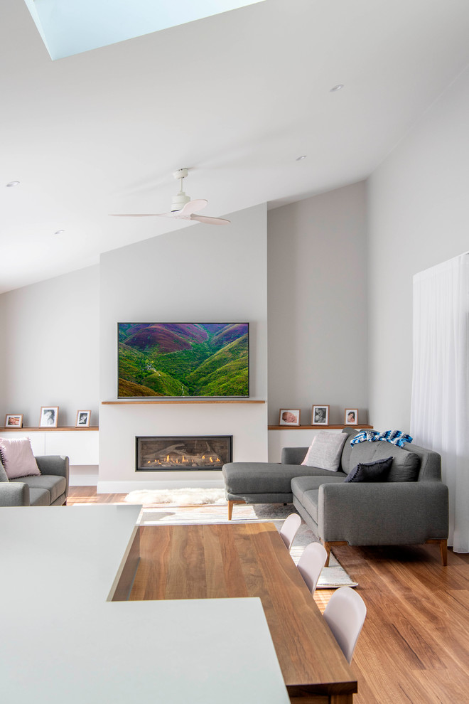 Photo of a medium sized contemporary formal open plan living room in Canberra - Queanbeyan with grey walls, medium hardwood flooring, a plastered fireplace surround, a ribbon fireplace and brown floors.