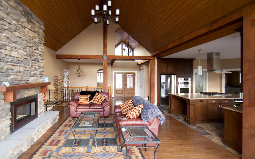Imagen de salón para visitas abierto tradicional con paredes beige, suelo de madera en tonos medios, todas las chimeneas y marco de chimenea de piedra